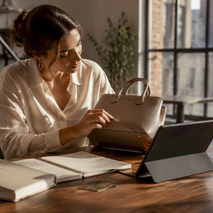 Woman checking designer fashion items on smartphone and handbag