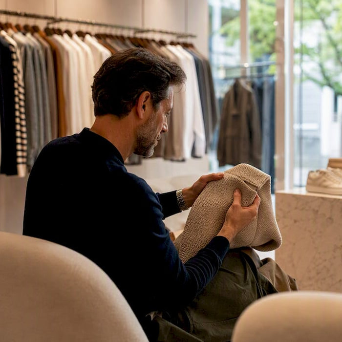 Hands inspecting garment stitching and fabric texture