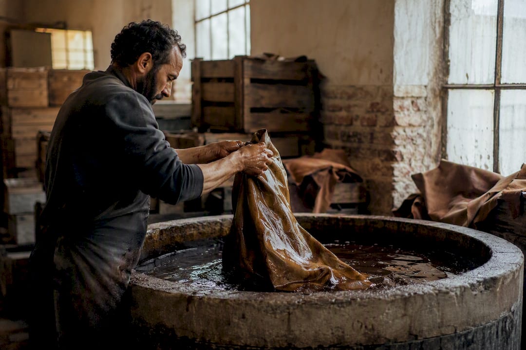Hands dipping leather in vegetable tanning vat