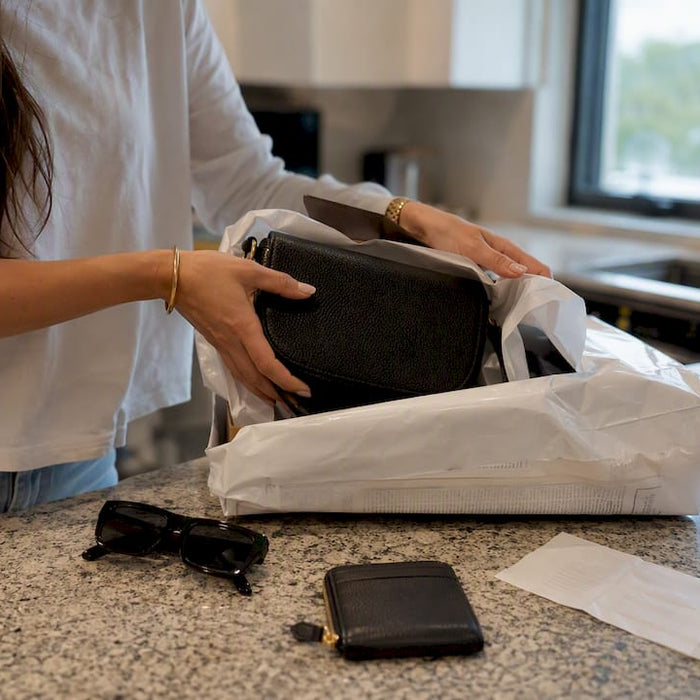 Hands unboxing parcel with designer bag