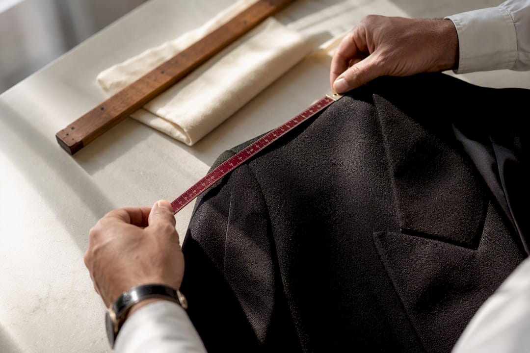 Hands measuring a tailored garment seam