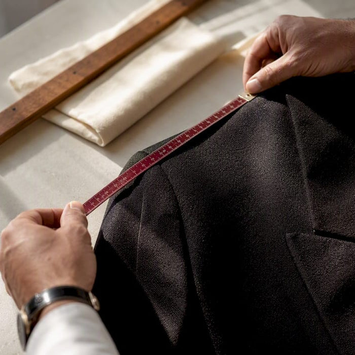 Hands measuring a tailored garment seam