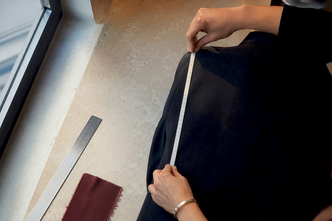 Stylist measuring anonymous tailored garment