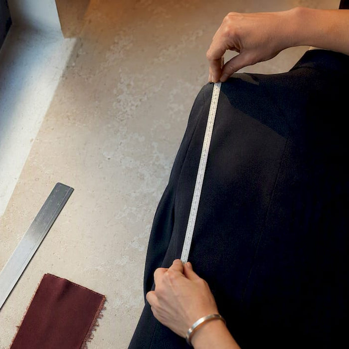 Stylist measuring anonymous tailored garment
