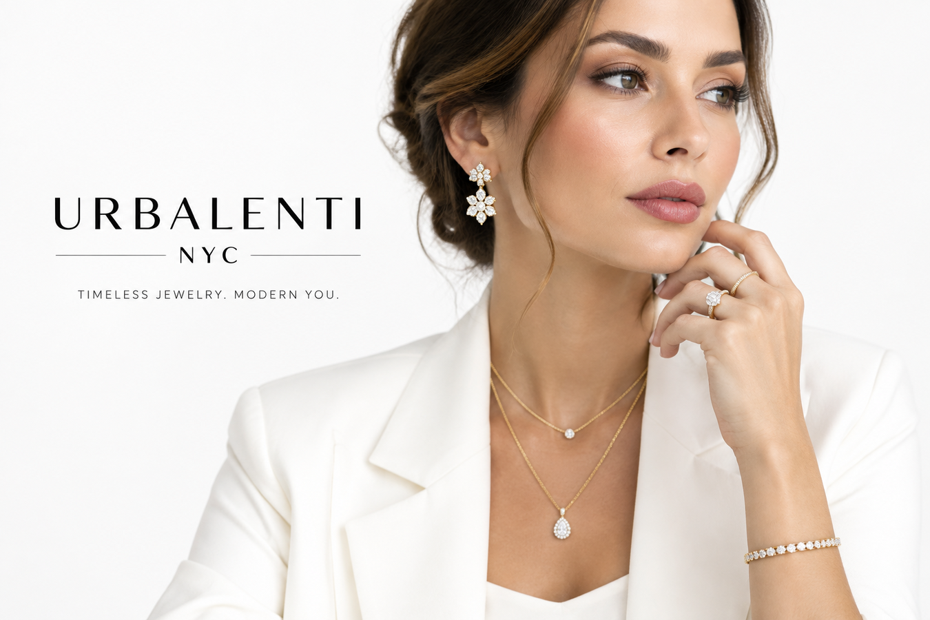 Women's Designer Jewelry featuring a woman wearing elegant layered necklaces, statement earrings, rings, and a bracelet with a white blazer—Shop Women's Luxury Designer Jewelry at Urbalenti NYC