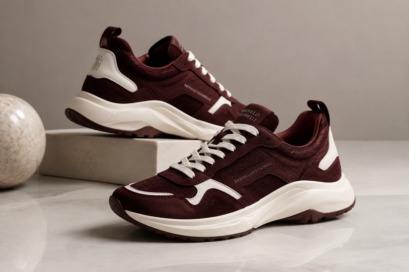Burgundy and white designer athletic sneakers displayed on a modern pedestal, showcasing Designer Athletic Shoes for Women. Shop Designer Athletic Shoes Now at Urbalenti NYC.