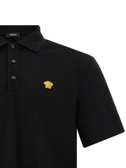 Close-up of the Versace Medusa Polo Shirt, highlighting the bold Medusa logo patch against the luxurious fabric, a staple piece by Versace for the Fall - Winter 2026/2027 collection. A chic choice for men's clothing and fashion. Men > Clothing > Shirts.