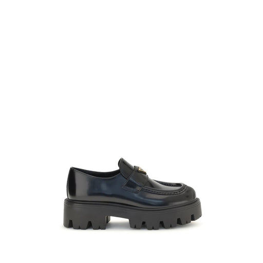 Prada Black Brushed Leather Slip-On Loafers for Women with Triangle Logo, side view showing polished calf leather, rounded toe, stitched apron, and chunky monobloc rubber sole. Prada Loafers for Women from Urbalenti NYC, style 13879, SKU 79661334579, Black, Discount_30-39, available in EU36.5/US6.5, EU36/US6, EU37/US7, EU38.5/US8.5, EU39/US9, and EU40/US10; in-stock, Loafers - Shoes, New with tags, Prada, Shoes, Slip-On Loafers - Loafers - Shoes, Women.