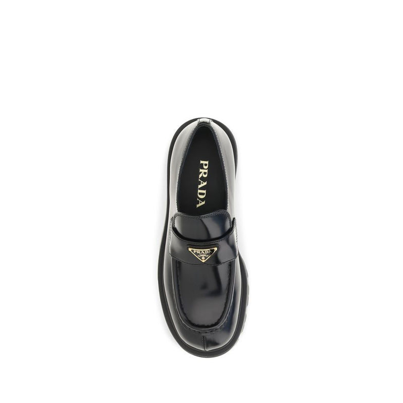 Prada Black Brushed Leather Slip-On Loafers for Women with Triangle Logo, top-down view showcasing the rounded toe, stitched apron, leather vamp strap, gold-tone Prada triangle emblem, and branded insole. Prada Loafers for Women from Urbalenti NYC, style 13879, SKU 79661334579, Black, Discount_30-39, available in EU36.5/US6.5, EU36/US6, EU37/US7, EU38.5/US8.5, EU39/US9, and EU40/US10; in-stock, Loafers - Shoes, New with tags, Prada, Shoes, Slip-On Loafers - Loafers - Shoes, Women.