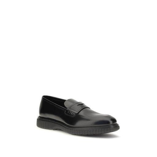 Front three-quarter view of Ferragamo Black Calf Leather Gancini Slip-On Loafers, Ferragamo Slip-On Loafers featuring a rounded toe, reversed vamp, polished black calf leather, Gancini ornament, and textured rubber sole. Shop at Urbalenti NYC, style 13879, item 79661334579, Black, Discount_40-49, available in EU39/US6, EU40/US7, EU41.5/US8.5, EU41/US8, EU42.5/US9.5, EU42/US9, EU43/US10, and EU44/US11; Ferragamo, in-stock, Loafers - Shoes, Men, New with tags, Shoes, Slip-On Loafers - Loafers - Shoes.