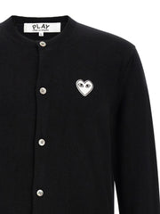 Close-up of the Comme Des Garçons Play heart logo and button-front detail on the Comme Des Garçons Play Black Wool Cardigan for Men. This Comme Des Garçons Cardigan for Men features Black wool knit construction and is New with tags, size L for Men, in-stock in Cardigans - Sweaters - Clothing, Clothing, and Sweaters - Clothing; Discount_30-39, 13879, 79680700467.