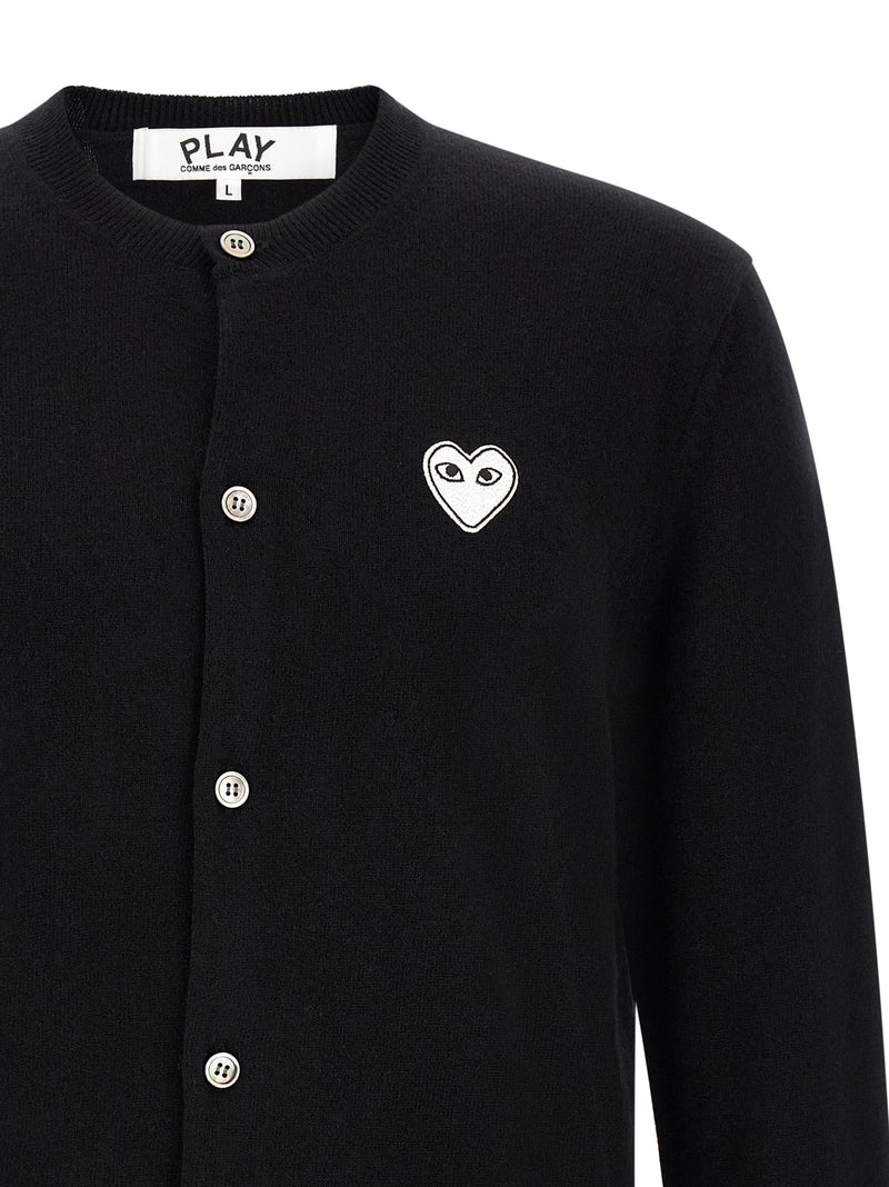 Close-up of the Comme Des Garçons Play heart logo and button-front detail on the Comme Des Garçons Play Black Wool Cardigan for Men. This Comme Des Garçons Cardigan for Men features Black wool knit construction and is New with tags, size L for Men, in-stock in Cardigans - Sweaters - Clothing, Clothing, and Sweaters - Clothing; Discount_30-39, 13879, 79680700467.