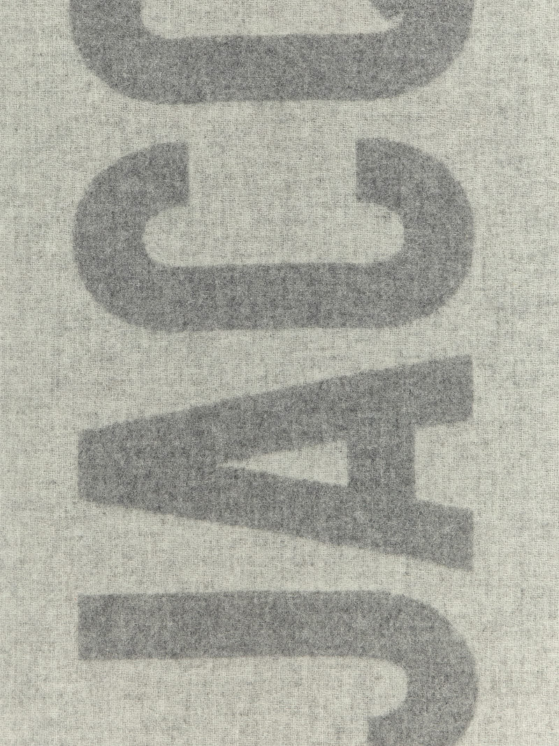 Jacquemus Wool Scarf, Jacquemus Gray Virgin Wool Scarf with Intarsia Logo and Fringes, detailed view of the bold gray intarsia logo on wool at Urbalenti NYC