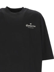 Close-up of the 032C Adidas x Willy Chavarria Printed Cotton T-Shirt displaying detailed branding on a black fabric, designed for stylish comfort by vendor 032C. This t-shirt is part of the LDin offerings for Men, within Men > Clothing, Men > Clothing > Topwear, designed for Spring - Summer 2026. Yes Eu.