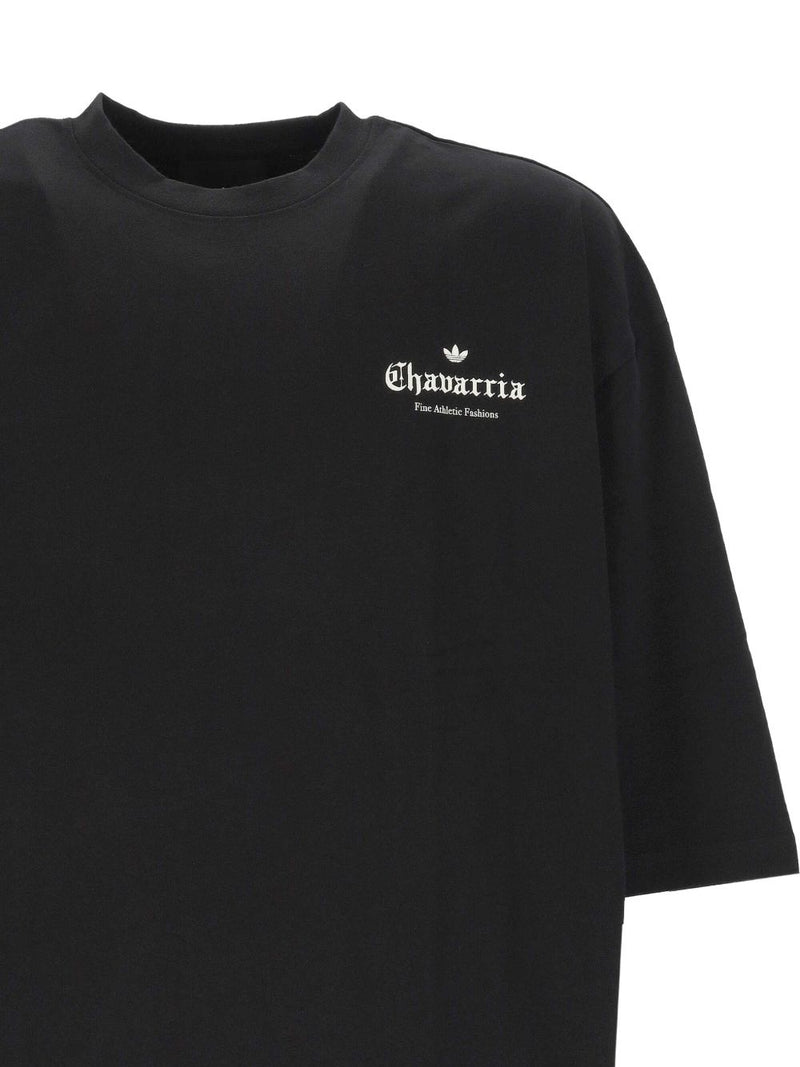 Close-up of the 032C Adidas x Willy Chavarria Printed Cotton T-Shirt displaying detailed branding on a black fabric, designed for stylish comfort by vendor 032C. This t-shirt is part of the LDin offerings for Men, within Men > Clothing, Men > Clothing > Topwear, designed for Spring - Summer 2026. Yes Eu.